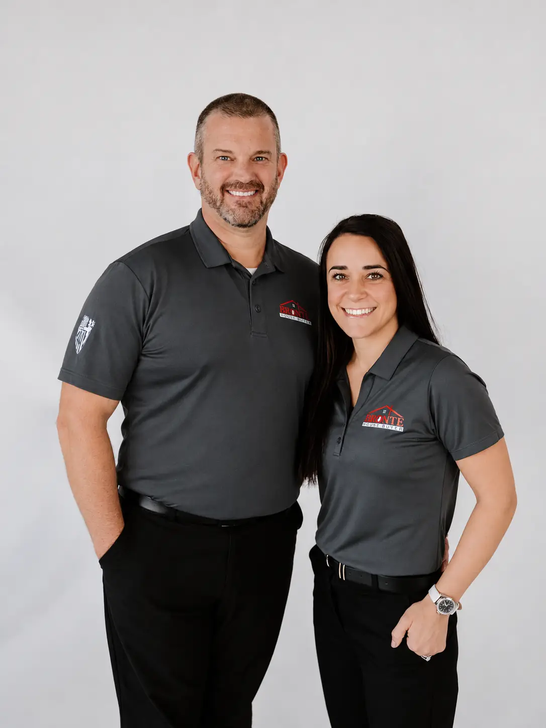 Jeremy and Cristine smiling side by side in gray Bronte House Buyer polos